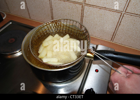 Qualcuno la frittura chip su un fornello in una coppa di chip Foto Stock