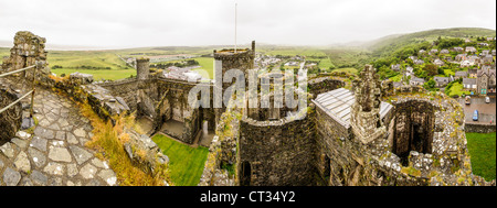 HARLECH, Galles: Una vista panoramica dalle merlature del castello di Harlech rivela le torri storiche, la città circostante, la campagna e Tremadog Bay in lontananza. Costruito tra il 1282 e il 1289 da Edoardo i durante la sua conquista del Galles, questo sito patrimonio dell'umanità dell'UNESCO si erge come uno dei migliori esempi di architettura militare della fine del XIII secolo in Europa. La posizione strategica del castello in cima a un affioramento roccioso forniva ai difensori una vista dominante sui potenziali approcci. Il castello di Harlech faceva parte dell'"anello di ferro" di Edoardo i di fortezze progettate per accerchiare e controllare il Galles del Nord. Nonostante Foto Stock