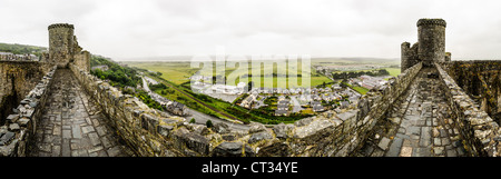 HARLECH, Galles - Una vista panoramica catturata dalle merlature del castello di Harlech, una fortezza medievale costruita alla fine del XIII secolo durante la campagna di re Edoardo i per conquistare il Galles. Costruita tra il 1282 e il 1289 come parte dell'"anello di ferro" di Edoardo, la roccaforte occupa una posizione strategica in cima a un affioramento roccioso che domina la Baia di Cardigan. Il sito Patrimonio dell'Umanità dell'UNESCO presenta un design concentrico con massicce mura e torri in pietra che hanno resistito a secoli di assedi e conflitti. Un tempo collegato direttamente al mare tramite una porta d'acqua, il castello si erge ora a circa 800 metri di distanza Foto Stock