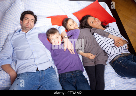 Famiglia la posa sul letto insieme Foto Stock