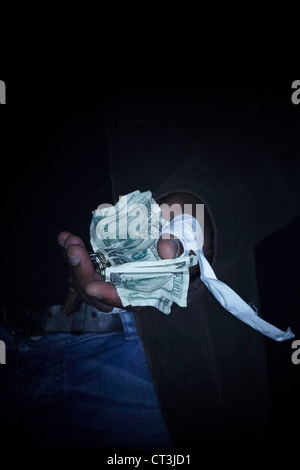 Mano azienda imbottita le fatture del dollaro nel buio Foto Stock