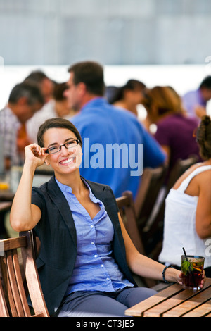 Bella e giovane donna seduta in un giardino di un ristorante e si gode la sua pausa dal lavoro. Foto Stock