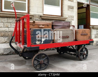 Vecchi tronchi di viaggio su un carrello bagagli, Swanage Stazione, Dorset, Regno Unito Foto Stock