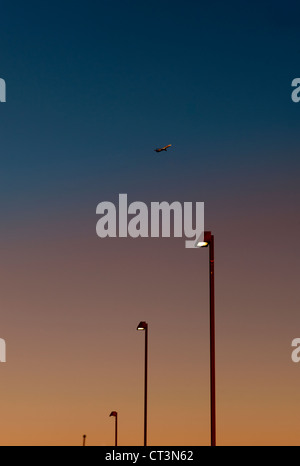 Aeroplano sopra le luci di strada al tramonto Foto Stock