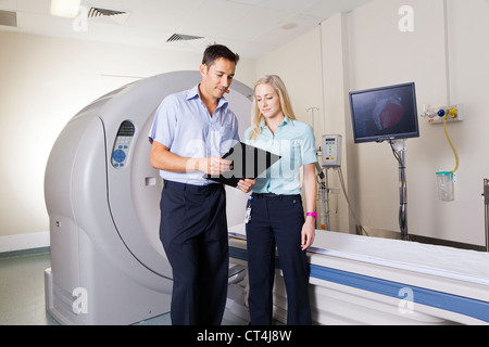 Giovane medico e infermiere in piedi di fronte a uno scanner MRI Foto Stock