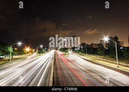 Auto sentieri di luce su Lake Shore Drive con la skyline di Chicago in background di Chicago, IL Foto Stock