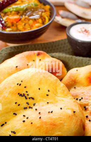 Fresco cotto al forno da pane naan indiano, con il burro e la cipolla semi, dal e yogurt in background. Foto Stock