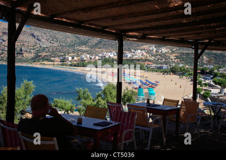 Uomo seduto con i drink, godendo della vista dal Castello snack bar, Paleochora vilage, Creta, Grecia Foto Stock
