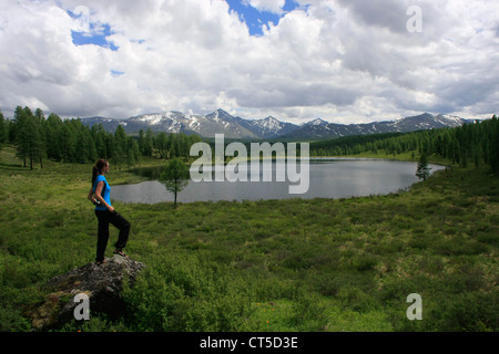 Donna in piedi su una roccia da incontaminato lago di montagna, Ulagansky pass, Altai, Siberia, Russia Foto Stock