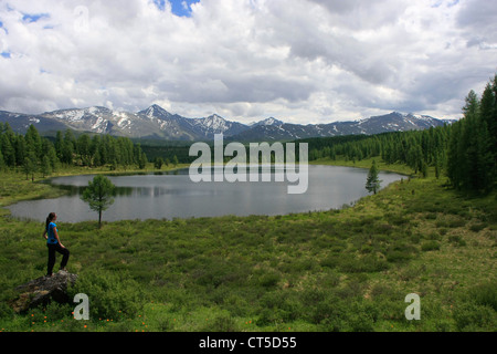 Donna in piedi su una roccia da incontaminato lago di montagna, Ulagansky pass, Altai, Siberia, Russia Foto Stock