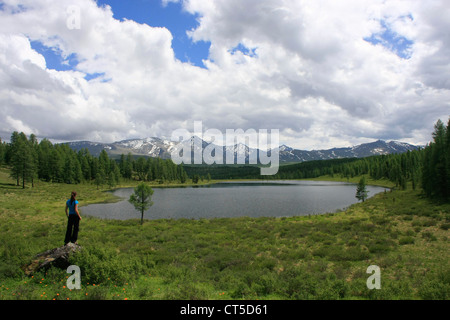 Donna in piedi su una roccia da incontaminato lago di montagna, Ulagansky pass, Altai, Siberia, Russia Foto Stock