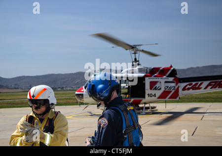 Foto di due membri di un reparto antincendio Elisoccorritori adatti per un esercizio. Elicottero in background Foto Stock