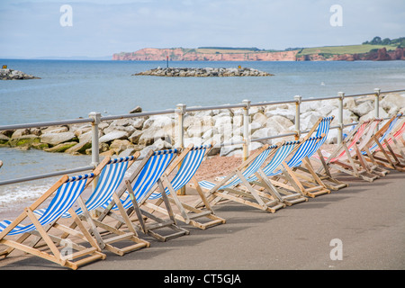 Fila di vuoto sdraio a strisce lungo la passeggiata a Sidmouth, nel Devon, Inghilterra, Regno Unito Foto Stock