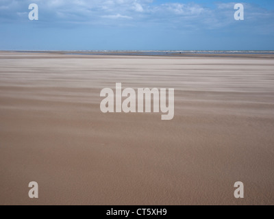 Una vista di Camber Sands in una giornata di vento con sabbia soffiando attraverso la spiaggia con il blu del cielo Foto Stock