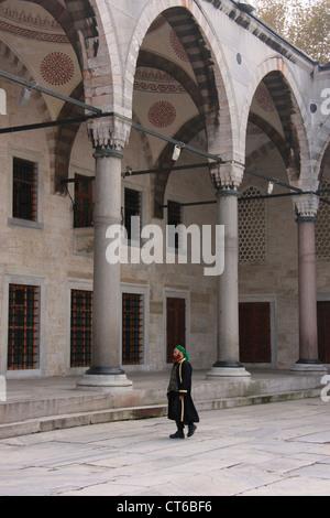 Uomo musulmano in abito tradizionale a piedi nel cortile interno del Sultano Ahmed, la Moschea di Sultanahmet, Istanbul, Turchia Foto Stock