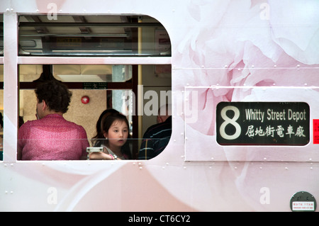 Ragazza giovane guardando fuori della finestra mentre viaggia su un hong kong tram Foto Stock