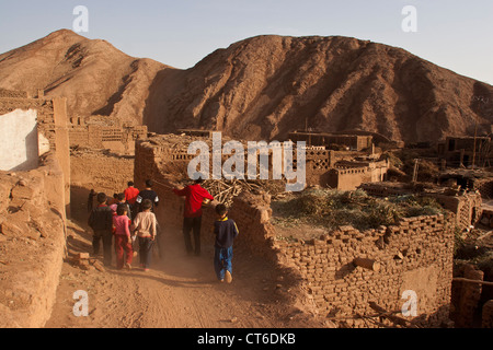 Gli abitanti di un villaggio con strumenti musicali a piedi attraverso Maza village vicino a Turpan, Xinjiang, Cina Foto Stock