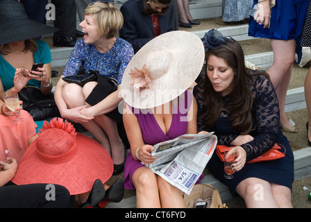 Vestito nuovo, donna anziana che mostra la sua scollatura. Due donne che leggono il giornale insieme sedute Un giorno alle corse, corse di cavalli Royal Ascot, Berkshire Inghilterra 2012, 2010s UK HOMER SYKES Foto Stock