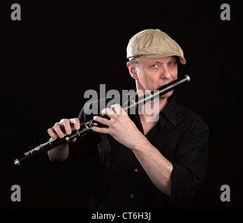 Ritratto di un uomo giocando in legno ols flauto traverso, isolato su nero Foto Stock