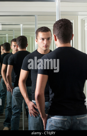 Bel giovane fissando se stesso nello specchio Foto Stock