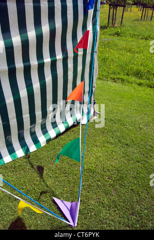 Bunting al vento attaccato ad un verde e bianco gazebo strippato sull'erba Foto Stock