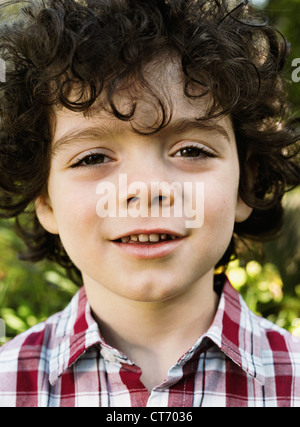 Un giovane ragazzo 5-8 anni con ricci capelli castani. Foto Stock