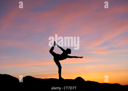 Giovane donna in posizione del signore della danza nel deserto, silhouette Foto Stock