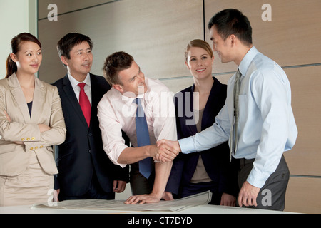 Multi razziale imprenditori stringono le mani su cianografia Foto Stock