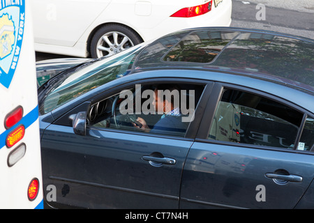 Donna lady driver utilizzando il telefono cellulare durante la guida la sua auto nel traffico nella città di New York Foto Stock