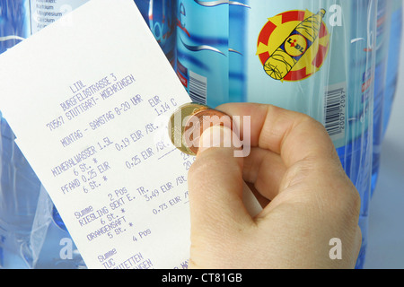 La mano con il denaro e la ricevuta di deposito prima di bottiglie di Lidl Foto Stock