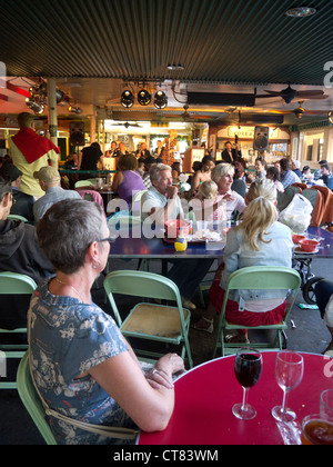 Donna seduta al tavolo di ascolto di musica dal vivo nel mercato degli agricoltori, Los Angeles Foto Stock