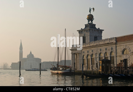 La galleria d'arte Punta della Dogana (di Tadao Ando) sul Canal Grande a Venezia, all'alba, con la torre di San Giorgio maggiore in lontananza Foto Stock