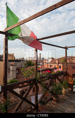La bandiera italiana che sorvola una 'altana' sul tetto di una casa a Venezia - una piattaforma in legno usata come giardino pensile Foto Stock