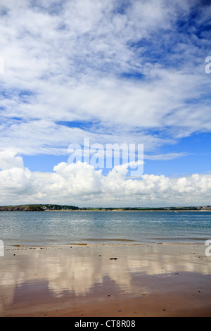 Cumulus nuvole riflettono in spiaggia a isola di Caldey, Pembrokeshire, con vista della spiaggia del Nord, Tenby in background. Foto Stock