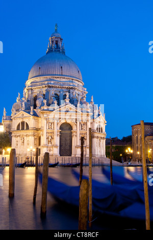 Chiesa di Santa Maria della Salute, con gondole in primo piano da tutto il Canal Grande al crepuscolo / notte Venezia Veneto Italia Foto Stock