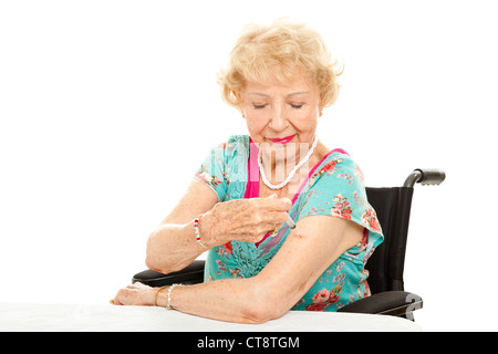 Senior donna in una sedia a rotelle, di darsi un'iniezione. Sfondo bianco. Foto Stock