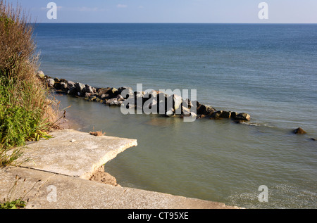 Una vista della vecchia costruzione di fondazioni a strapiombo sul bordo scogliera a causa di erosione costiera a Happisburgh, Norfolk, Inghilterra, Regno Unito. Foto Stock