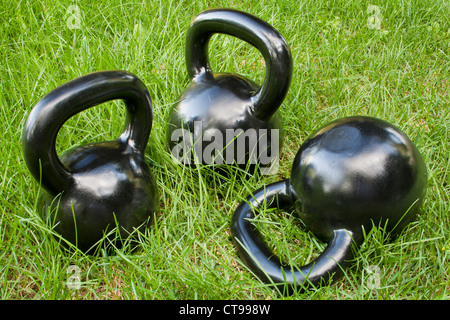 Tre pesante ferro kettlebells in erba verde - outdoor concept fitness Foto Stock