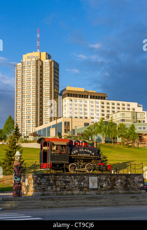 Alaska Railroad storica statua del treno con il centro di Anchorage, Alaska, hotel in background. Foto Stock