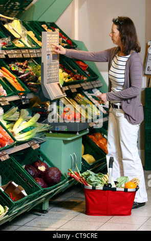 La donna è lo shopping in un grande supermercato. La frutta e la verdura al reparto. Foto Stock
