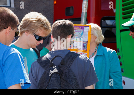 Giovani turisti controllare il bus turistico hop on / off volte nel popolare, affollata e piena di jazz Nyhavn in un caldo giorno d'estate e di sole Foto Stock