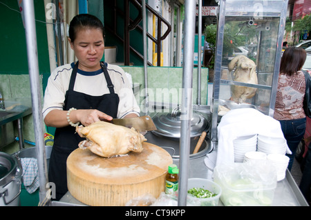 Un cibo titolare di stallo tagliare un pollo arrosto in una delle strade laterali a Bangkok, in Thailandia Foto Stock