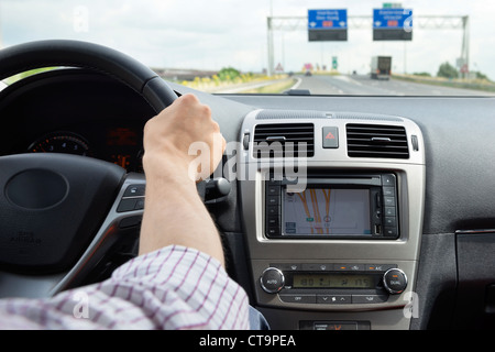 Mano sul volante di una moderna e lussuosa auto, prendendo un'uscita su una autostrada Foto Stock