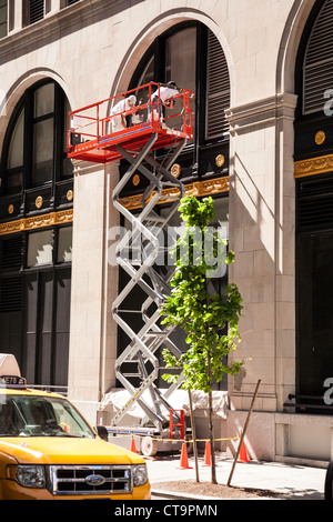 I lavoratori di completare il recupero edilizio sul tavolo elevatore a parallelogramma, NYC Foto Stock