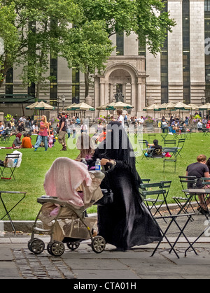 Un sistema completamente donna musulmana velata spinge un passeggino in Bryant Park di New York City. Nota Biblioteca Pubblica di New York in background. Foto Stock