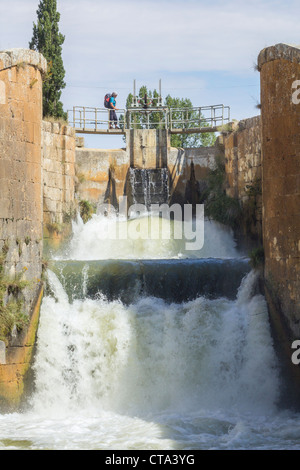 Escursionista femmina sul canal cancelli di blocco a El Serron. Canal de Castilla, Palencia, provincia, Spagna. Foto Stock