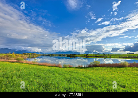 Lago Riegsee nella luce del sole di primavera e sullo sfondo la città di Murnau, montagne del Wetterstein con Zugspitze e Alpspitze Foto Stock