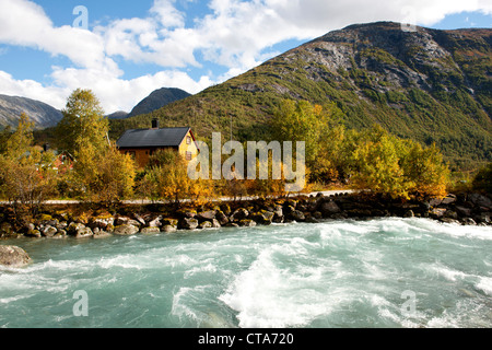 Tourquoise fiume colorato di fronte a una casa in legno, Autunno, sentiero per Nigardsbreen, Jostedalsbreen, Jostedalen, Sogn og Fjordan Foto Stock