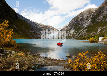 Vista di Nigardsbreen, rosso barca su un lago nel fronte del ghiacciaio muso, Autunno, Nigardsbreen, Jostedalsbreen national park, Jost Foto Stock