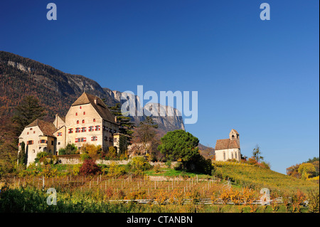 Manor House e Chiesa di vigneti in autunno colori con rockface in background, vicino al lago di Caldaro, Alto Adige, Italia, e Foto Stock